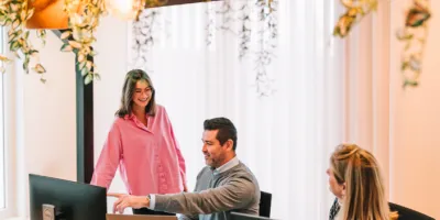 Trois collaborateurs échangent autour d’un bureau dans un environnement professionnel moderne et lumineux