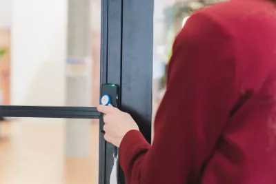 Person holding a badge to unlock a door with an access control reader