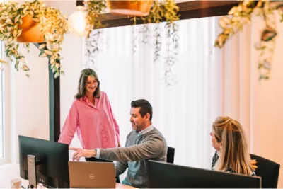 Three colleagues working together at a desk in a modern, well-lit office