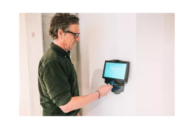 Employee clocking in with a badge at a wall-mounted time tracking terminal