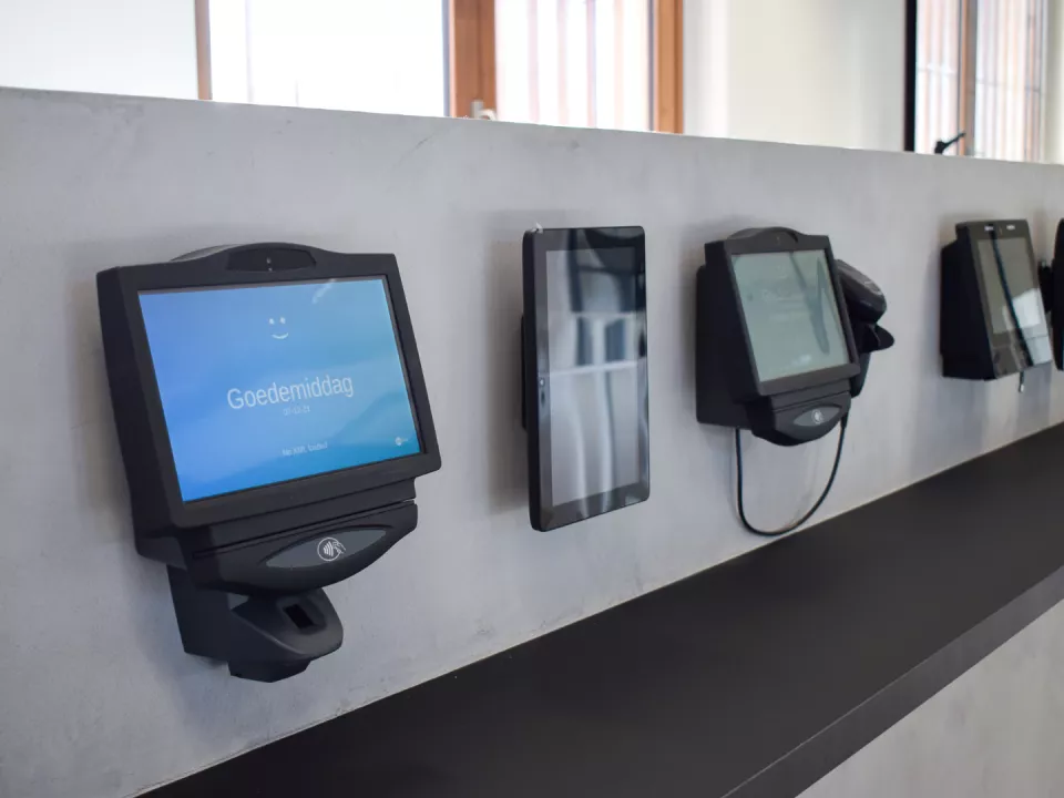 Row of wall-mounted time tracking terminals ready for employees to clock in and out