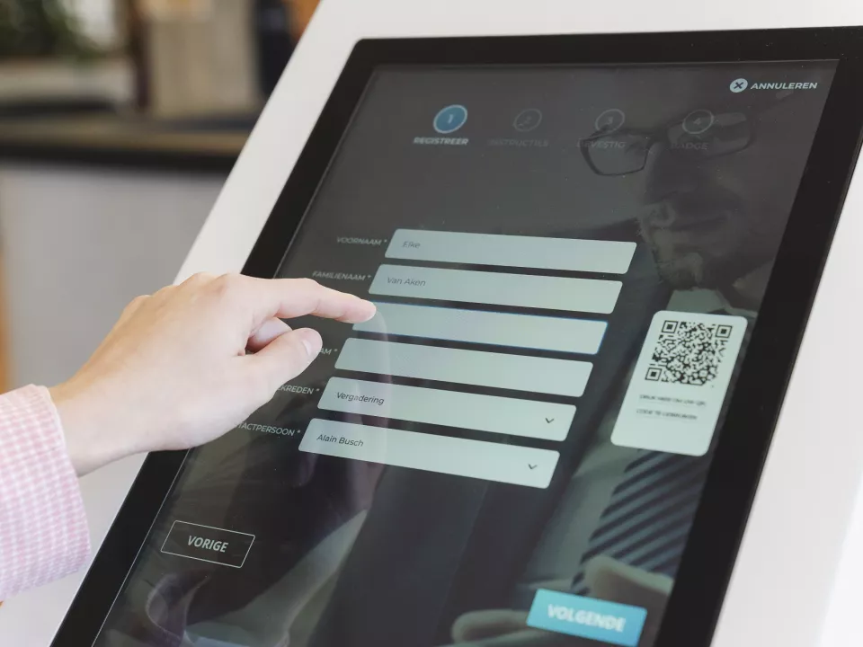 A visitor registering on a touchscreen kiosk at a building entrance